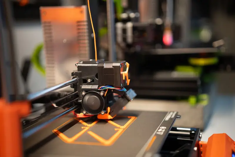Detailed view of a 3D printer head in action creating a design