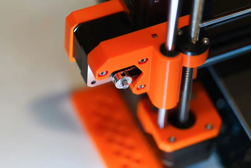 Detailed view of an orange 3D printer element with focus on mechanical parts