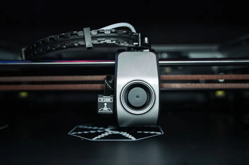 Detailed close-up of a 3D printer extrusion head in focus, showcasing modern technology