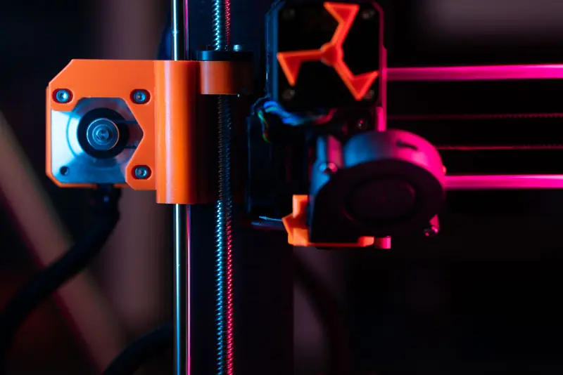 A detailed close-up of a 3D printer showcasing its extruder and components under vibrant lighting