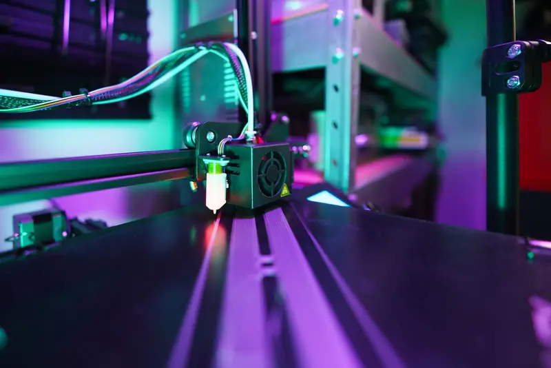 A detailed view of a 3D printer in operation with vibrant neon lighting creating a futuristic tech ambiance