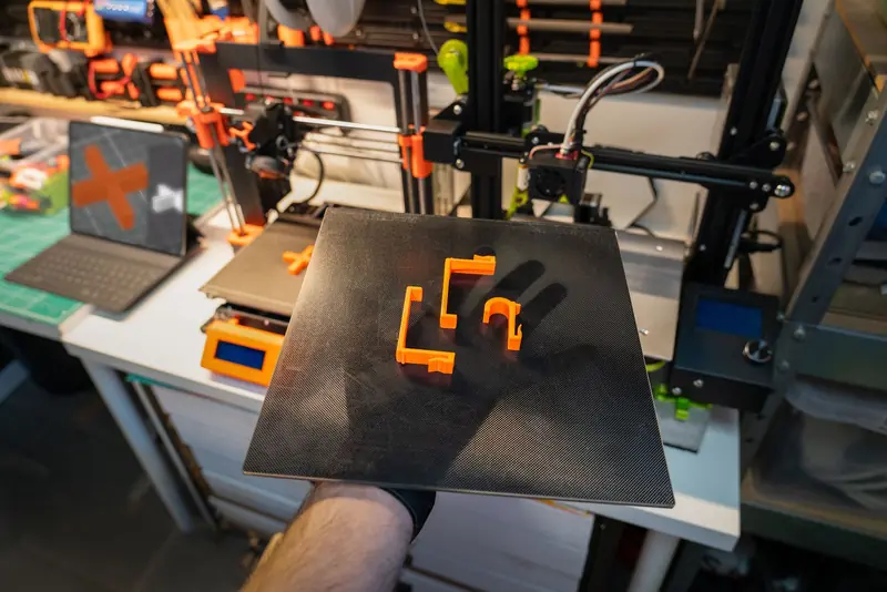 Close-up of a 3D printer and printed parts in a modern workshop setting