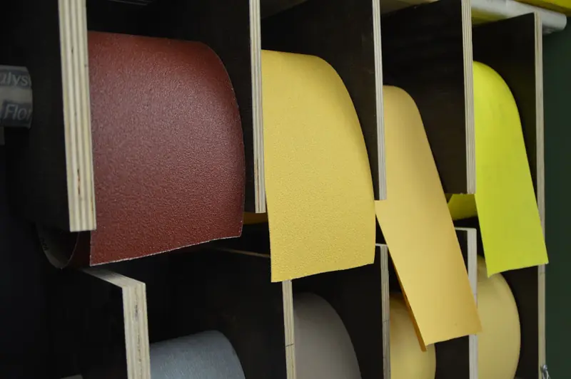 Close-up of colorful sandpaper rolls in an organized storage setup, showcasing different textures