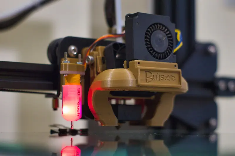Detailed shot of a 3D printer nozzle operating in a workshop setting