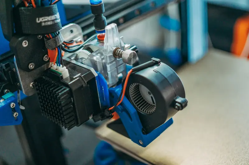 Detailed view of 3D printer parts showing wires and equipment in a workshop setting